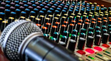 A microphone rests on a live sound mixing board